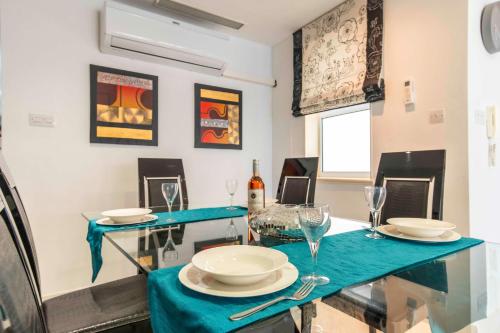 a dining room with a blue table with plates and glasses at Oceanfront 3BR Penthouse Luxury & Views in Sliema in Sliema