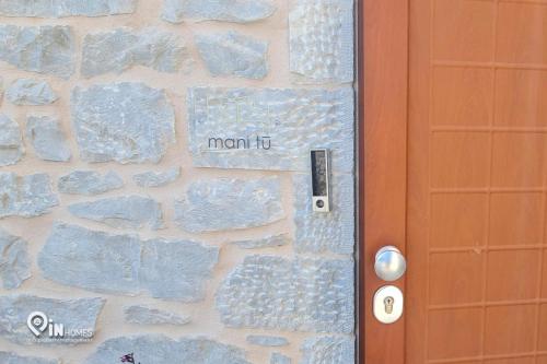 a door with a sign that reads mom next to a stone wall at Mani Tu With Breathtaking View 2 in Éxo Nímfion