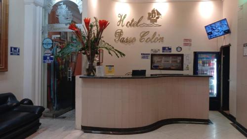 un vestíbulo con un mostrador con un jarrón de flores en hotel paseo colon inn, en Barranquilla