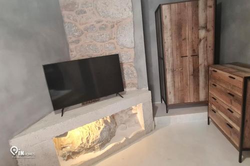 a fireplace with a flat screen tv on top of it at Mani Tu With Breathtaking View 2 in Éxo Nímfion