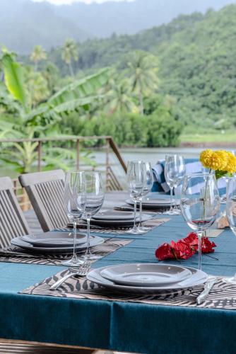 a table with glasses and plates on a blue table cloth at Villa Ho'a - bord de mer avec piscine in Papetoai