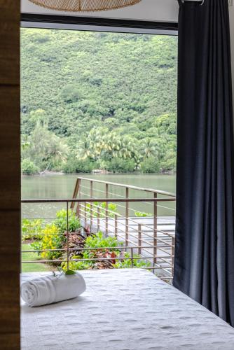 a bedroom with a view of a river from a window at Villa Ho'a - bord de mer avec piscine in Papetoai