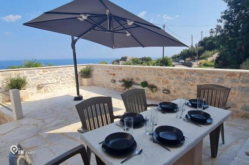 a table with chairs and an umbrella on a patio at Mani Tu With Breathtaking View 2 in Éxo Nímfion