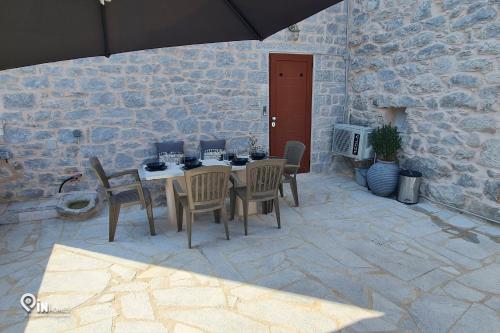 a patio with a table and chairs and an umbrella at Mani Tu With Breathtaking View 2 in Éxo Nímfion