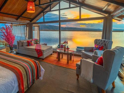 KAY PACHA LODGE lago titicaca All Inclusive في بونو: غرفة نوم بسرير وإطلالة على الماء