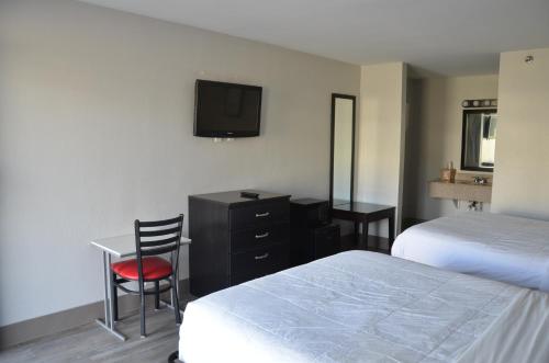 Habitación de hotel con 2 camas, escritorio y TV. en My Home & Suites Covington en Covington