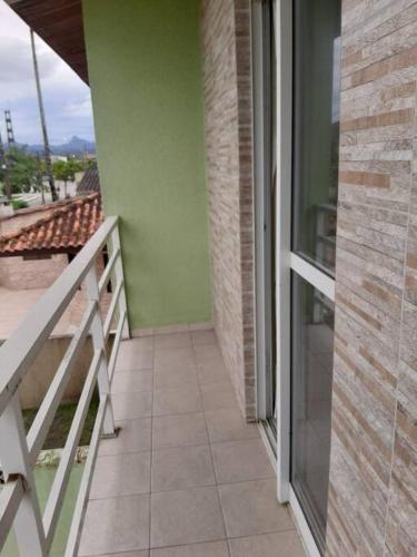 a balcony with a glass door and a tiled floor at Sobrado confortável a uma quadra do mar. in Matinhos