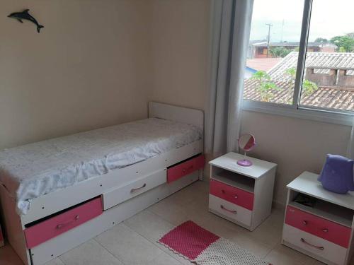 a small bedroom with a bed and a window at Sobrado confortável a uma quadra do mar. in Matinhos