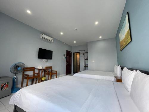 a bedroom with two beds and a table and a tv at An Nhiên Hotel in Tây Ninh