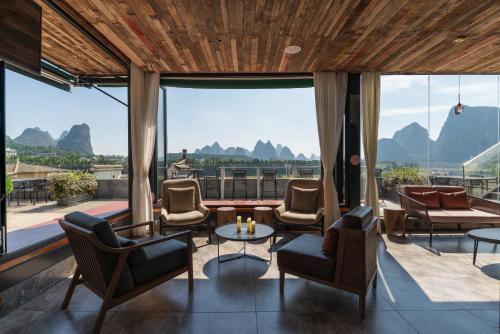 a living room with chairs and tables and large windows at Percent Hotel Yangshuo in Yangshuo