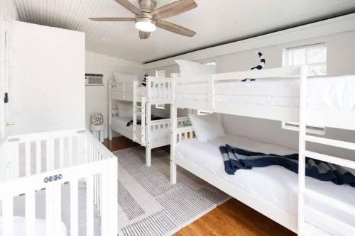 a bedroom with white bunk beds and a ceiling fan at Serenity Retreat Pool BBQ Swing Set WiFi+ in West Palm Beach