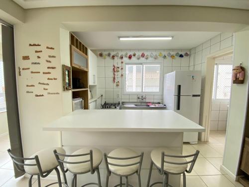 eine Küche mit einer großen weißen Theke und Stühlen in der Unterkunft Apartamento capão da canoa in Capão da Canoa