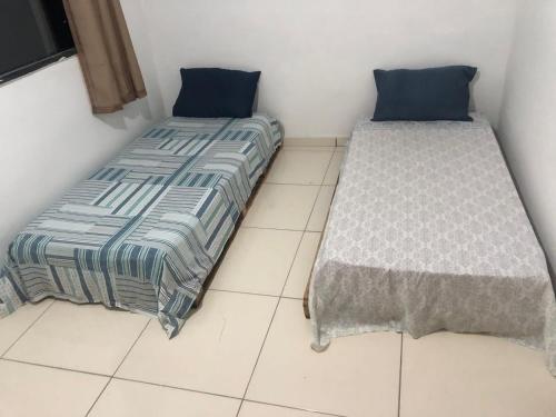 dos camas sentadas una al lado de la otra en una habitación en Tchê Hostel, en Porto Seguro