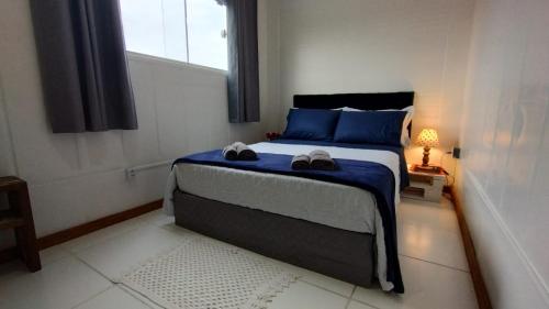 ein Schlafzimmer mit einem Bett mit blauen Kissen und einem Fenster in der Unterkunft Celebre Cama e Café (B&B) in Florianópolis