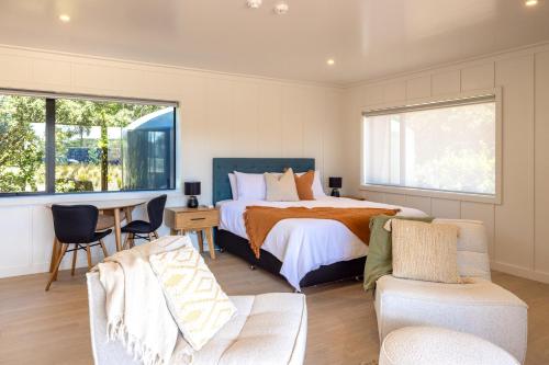 a bedroom with a bed and a table and chairs at Onetangi Beach Stays Studio 2 - Coast & Country in Onetangi