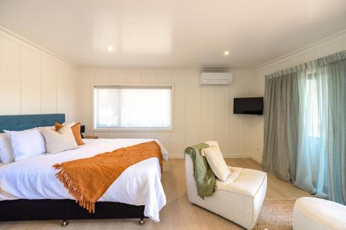 a bedroom with a large bed and a chair at Onetangi Beach Stays Studio 2 - Coast & Country in Onetangi