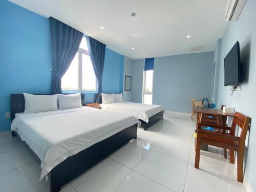 a bedroom with two beds and a desk and a television at An Nhiên Hotel in Tây Ninh