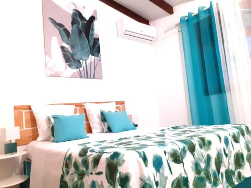 a bedroom with a bed with blue pillows and a plant at Agréable maison 3 pièces tout confort pour 4 personnes - Vue sur jardin in Saint-François