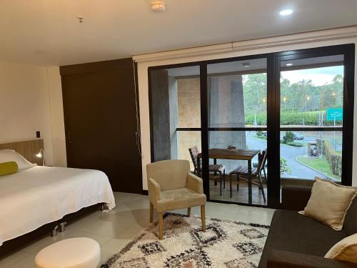 a bedroom with a bed and a balcony with a table at Towers Confort in Rionegro