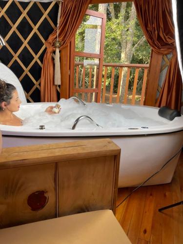 a woman sitting in a bath tub in a room at Glamping montain experience in São Joaquim