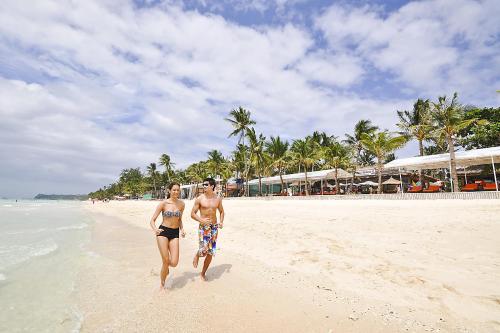 a man and a woman walking on a beach at Paradise Garden Hotel and Convention Center Boracay Powered by ASTON in Boracay