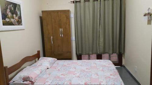 a bedroom with a bed and a curtain and a door at CASA PERO CABO FRIO a 60 Metros da praia in Cabo Frio