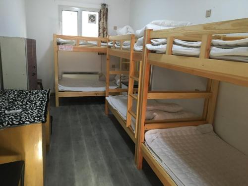 a room with three bunk beds and a window at P.Loft Youth Hostel in Beijing