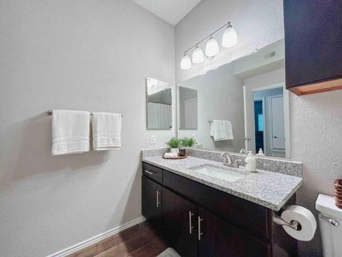 uma casa de banho com um lavatório e um espelho grande em Warm 2-Bedroom Amongst Shaded Oaks em Corpus Christi