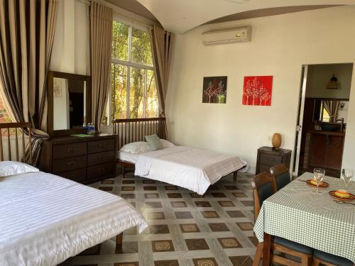 a bedroom with two beds and a table and chairs at Bình An Village in Vĩnh Long