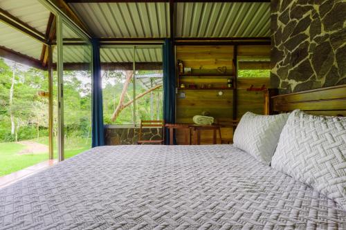 a bed in a room with a large window at Hotel Rivel - Restaurant & Nature Retreat in Turrialba