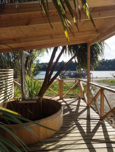 a wooden deck with a boat on the beach at Peumayen in Quellón