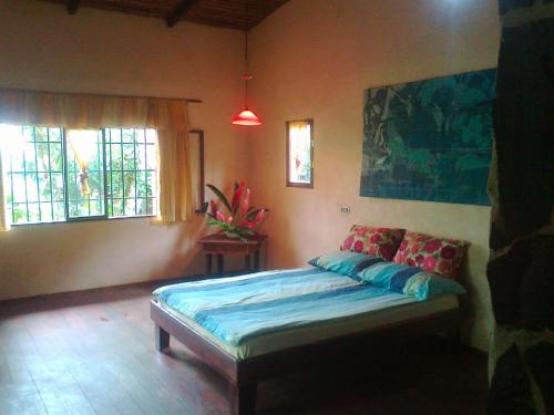 a bedroom with a bed and two windows at Vanilla Jungle Lodge - Rainforest Waterfall Garden in Puerto Viejo