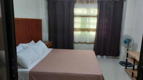 Schlafzimmer mit einem Bett und einem Fenster mit Vorhängen in der Unterkunft MANIPON TRANSIENT HOUSE in San Juan