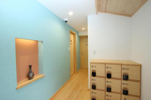 a room with a blue wall and a vase on a shelf at Mitsukuri Hotel in Tuyama