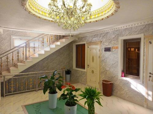 a living room with a chandelier and stairs with plants at Dari Zanjir in Samarkand