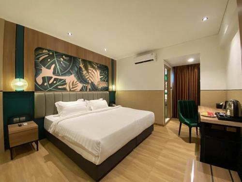 a bedroom with a bed and a desk with a chair at Alltrue Hotel Bintan - Tanjungpinang in Tanjung Pinang