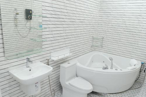 a bathroom with a tub and a toilet and a sink at Tulip Hotel in Louang Namtha
