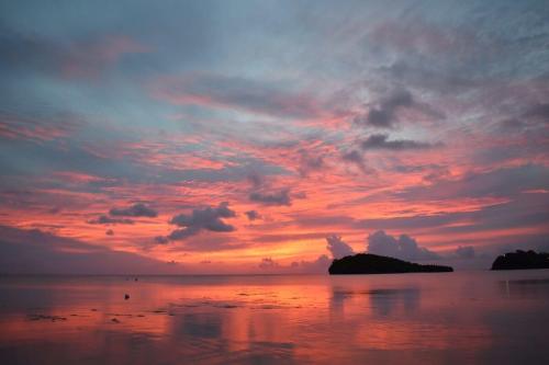 un coucher de soleil sur l'océan avec un ciel nuageux dans l'établissement Ocean Villa Guam, à Tamuning