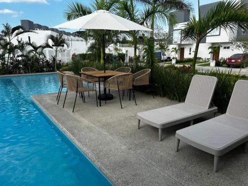 NaranjoにあるCasa Comoda Con Piscinaのプールサイドのテーブル(椅子付)とパラソル付