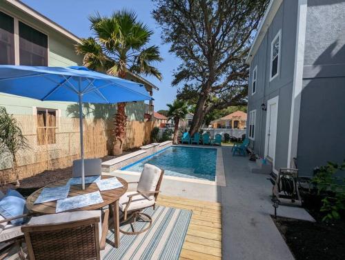 a patio with a table and an umbrella and a pool at 5/3 with a heated pool 2 min from beach, updated in Galveston