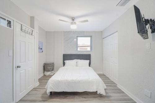 een witte slaapkamer met een bed en een plafondventilator bij Spacious and luxurious home centrally located between Miami and Ft. Lauderdale in Miramar