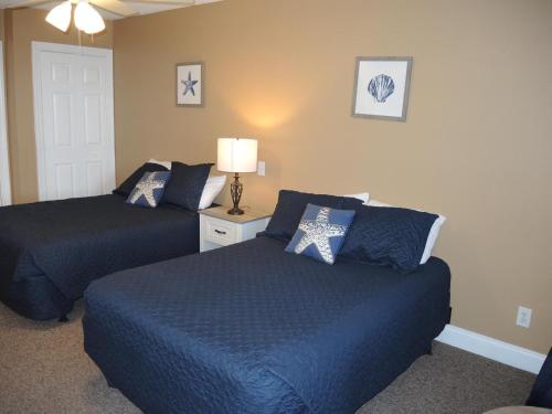 a bedroom with two beds with blue sheets and a lamp at Brunswick Plantation Studio Home 1301L in Calabash
