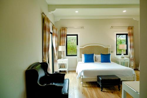 a bedroom with a bed with blue pillows and a chair at Chivani Pattaya in Na Jomtien