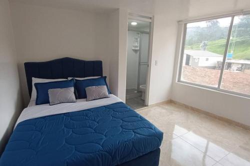 Santa Rosa de Viterbo的住宿－Apartamento Nuevo y Central，一间卧室设有蓝色的床和大窗户