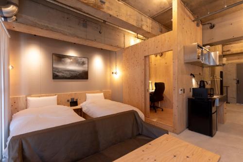 Zimmer mit 2 Betten und einem Schreibtisch. in der Unterkunft HAJIMARI Beppu in Beppu