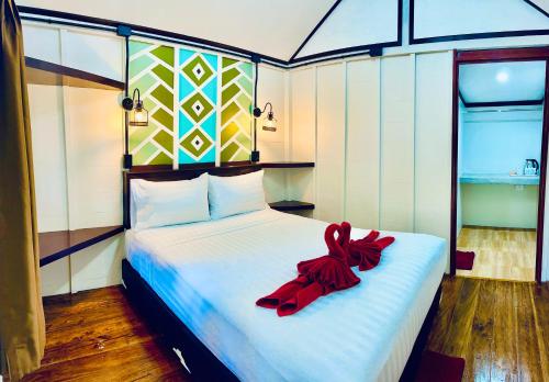 Un dormitorio con una cama con una cinta roja. en Lanta L.D. Beach Bungalow, en Ko Lanta