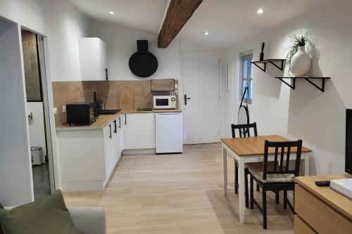 a kitchen with white cabinets and a table and a dining room at Charming studio in the historic centre in Montpellier