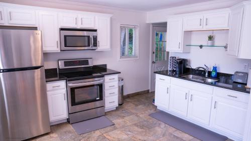 a kitchen with white cabinets and a stainless steel refrigerator at The Rock B&b W Firepit Near Downtown Birmingham in Birmingham