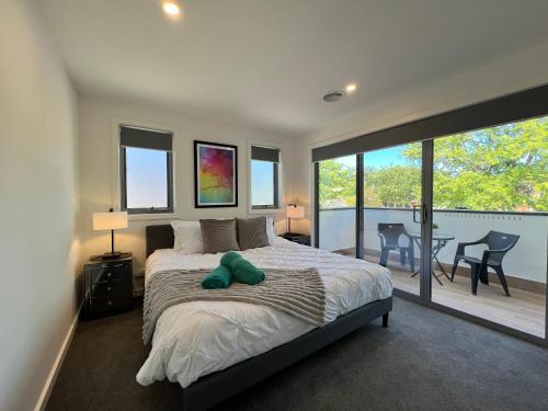 een slaapkamer met een bed met een groen knuffeldier erop bij Stunning Dickson Luxe 3BR 2Bath Double Garage WiFi Brand New Home in Canberra