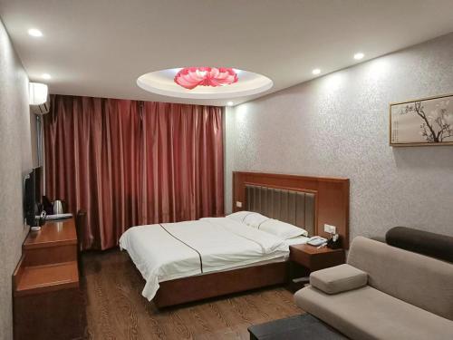 a bedroom with a bed and a room with a couch at Harbin Huaxi Hotel - Ice World Branch in Harbin